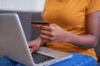 © Meeko Media - A close up of a young woman holding a credit card and shopping online