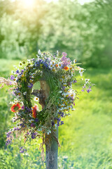 rustic wildflowers wreath in garden, sunny day. Farm lifestyle. Summer Solstice Day, Midsummer. floral traditional decor. pagan witch traditions, wiccan symbol and rituals