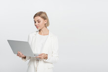 Blonde Businesswoman Looking At Laptop Isolated On Grey.