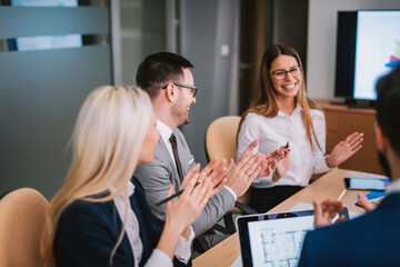 Cheerful businesspeople applauding a in a meeting at boardroom.