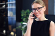© sashka_lenka - Portrait of stylish elegant woman in glasses with cellphone in modern office. Bussiness concept.