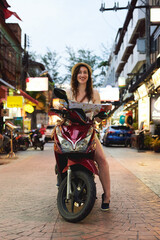 Canvas Print - Travel while youre young. Portrait of a young woman using a map while travelling on a scooter in a foreign city.