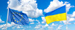 Waving Ukraine and European Union flags against blue sky with clouds.