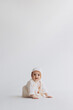 © Ananass - Cute studio portrait of a little newborn girl posing for a photo on a light background. A baby who has already learned to crawl and sit