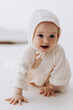© Ananass - Cute studio portrait of a little newborn which has already begun to crawl. The child laughs and rejoices in his first little steps
