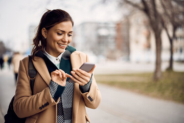 happy woman text messaging on cell phone in the city.