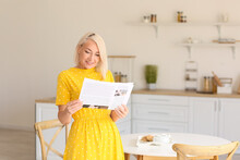 Beautiful Mature Woman Reading Newspaper In Kitchen