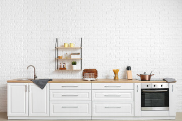 Interior of modern kitchen with white counters and empty glasses