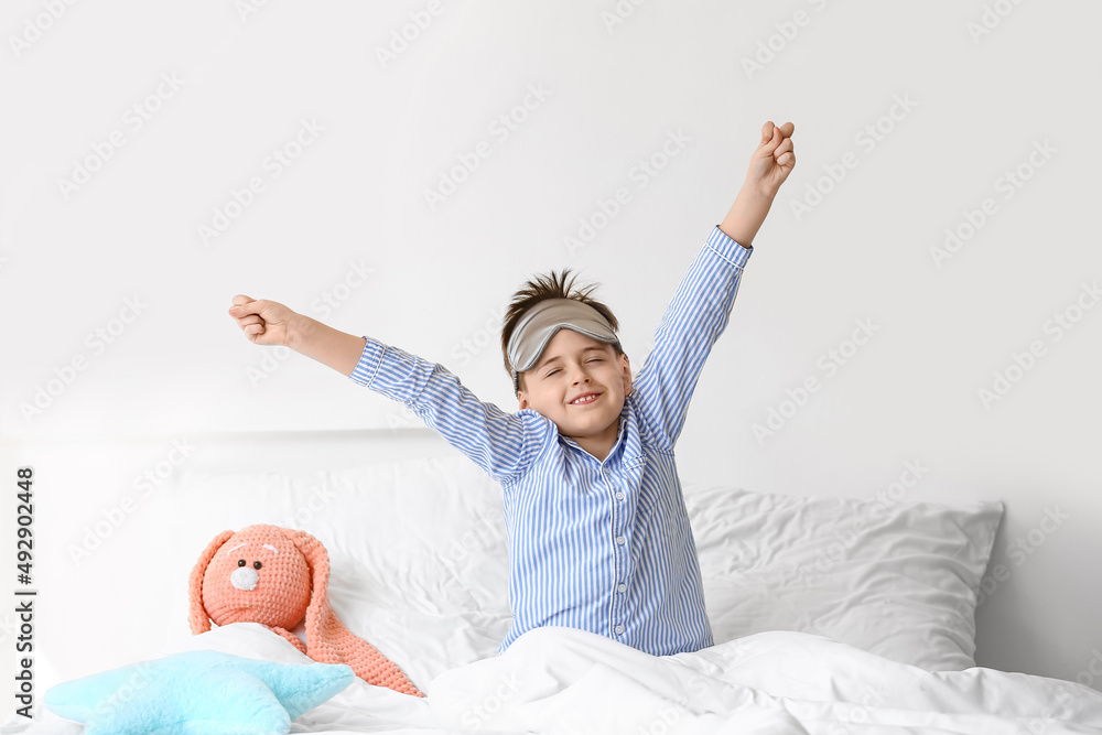 Little boy with sleep mask in bed