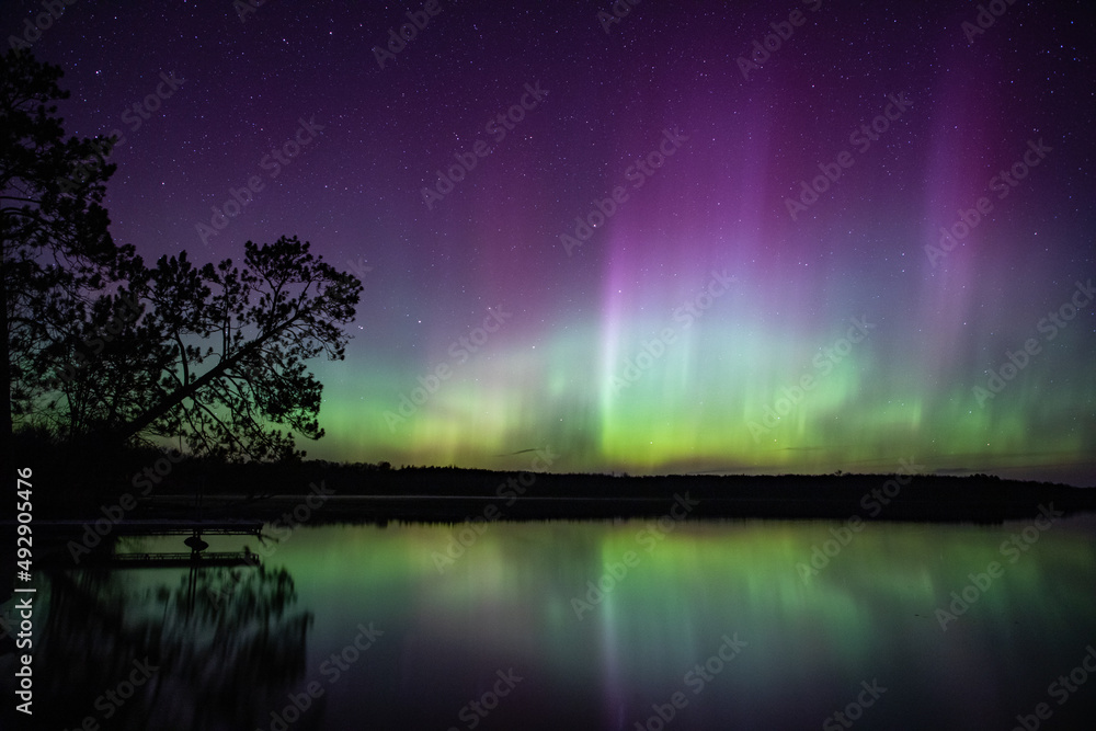 Northern lights erupt above a lake in Northern Minnesota in the dark ...