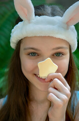 Wall Mural - Beautiful little kid with funny bunny headband cleansing her face by yellow star  shape sponge. Portrait of cute little teenage girl enjoying skin care procedures