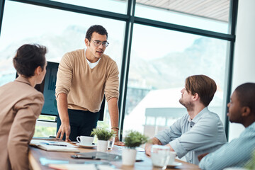 Wall Mural - Lets consider some new strategies. Shot of a young businessman giving a presentation to his colleagues in an office.