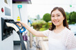 © DG PhotoStock - Unrecognizable Asian woman holding a DC - CCS type 2 EV charging connector at EV charging station.