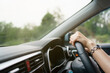 © DG PhotoStock - Unrecognizable female driver using left hand grabs on the steering wheel while driving on the road.