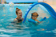 © ninelutsk - Toddler child learning to swim in indoor swimming pool with teacher. Floating in the water, balancing and general physical activity for kids, early development. Boy kid trained to kick legs and float