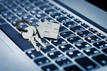 Sticker - House key and home symbol shaped keychain on laptop keyboard online internet property search concepts