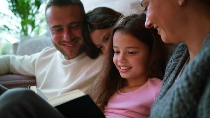 Wall Mural - Two happy sisters with mother and father sitting on floor hugging and reading book at home