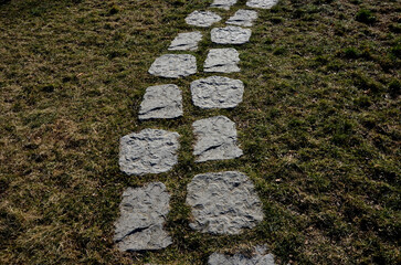 gray stone in a garden with a stone nature path to the arches near the lawns covered with snow. garden walkway made of slate boards side by side in lawn park architecture. ornamental, muddy