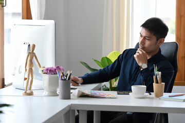 Wall Mural - Focused young man office worker reading information on modern computer.