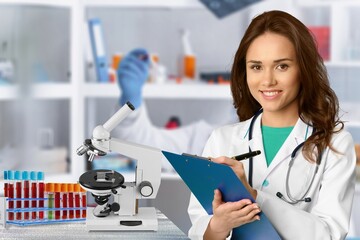 Wall Mural - Serious scientist in lab coat a medical research laboratory. Student holding clipboard and taking notes summarising information for scientific report