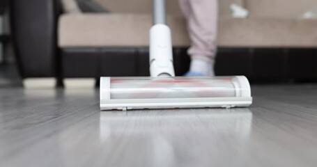 Wall Mural - Housewife cleans house with cordless vacuum cleaner closeup