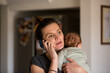 © ReeldealHD images - New Mum on phone looking worried whilst holding newborn