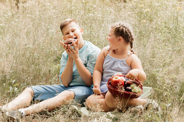 children eating lunch outdoors. Kids on picnic  in spring garden. Preschooler girl and skool  boy eat and drink in summer park