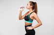 © khmelev - Strong sporty caucasian woman in black fitness suit drinks water on isolated gray background