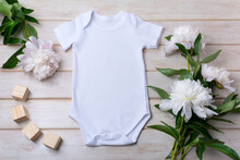 White Baby Short Sleeve Bodysuit Mockup With Peony And Toy Blocks