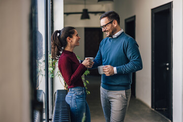 Wall Mural - Two colleagues taking a break from work, drinking coffee, talkin