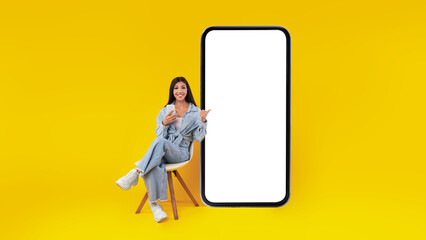 Happy lady using mobile phone pointing at gadget at studio
