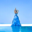 Elegant fashion model near the pool. Glamour woman in elegant long gown dress on the Maldives beach.Travel model. Elegance. Bride on Maldives. Bridal fashion. Pretty woman in long dress near the pool.