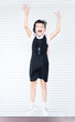 Verticsl portrait of 9 years old happy caucasian jumping school girl on white background with hands up. Happy girl wants to learn. Smiling child in school uniform jump