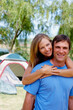 © Stigur/peopleimages.com - Loving couple. Portrait of couple camping with woman embracing man from behind.