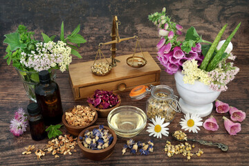 Flowers and herbs with essential oil bottles used in aromatherapy treatments. Alternative herbal plant medicine and flower remedies,  natural health care concept. Top view, on rustic wood.