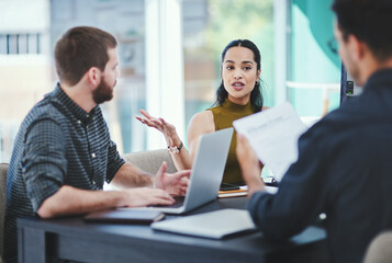 Poster - Arranging plans down to the detail. Shot of a group of young designers having a discussion in an office.