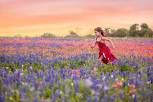 Girl In Red Dress Running In Texas Wildflower Field