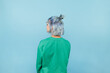 © bodnarphoto - Hipster girl with blue hair stands with her back to the camera on a blue background and looks away, wearing a green sweatshirt
