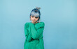 © bodnarphoto - Cute hipster girl with blue hair isolated on blue background posing at camera in green sweatshirt.