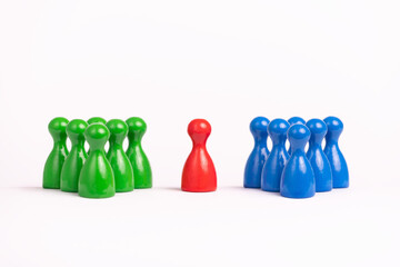 choice, decision, indecision, the agony of choice: one red game piece between a group of green and a group of blue toy figures, white background