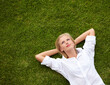 © Marine G/peopleimages.com - So much to ponder.... High angle shot of an attractive young woman relaxing on a grassy field and looking up at the sky.