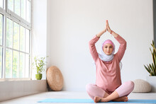 Young Pregnant Muslim Woman Doing Yoga On Mat At Home
