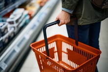 Close-up Of Woman With Empty Shopping Basket By Diary Aisle At Grocery Store.
