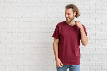 Wall Mural - Handsome young man in t-shirt on white brick background