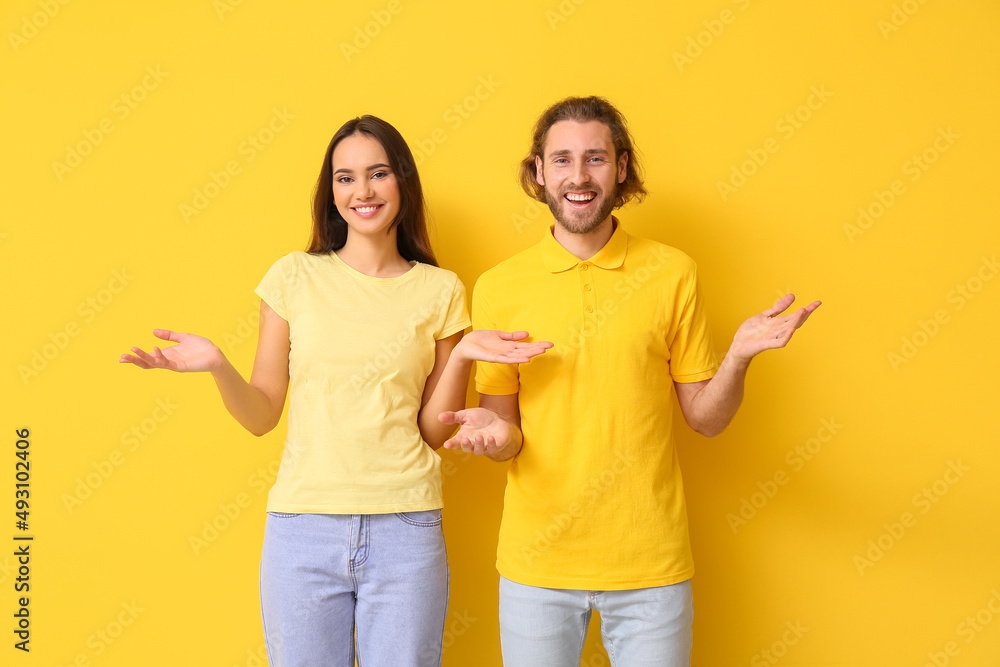 Young couple in stylish t-shirts on yellow background