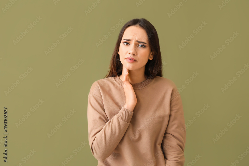 Young woman suffering from sore throat on color background