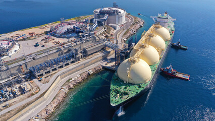 Aerial drone photo of LNG (Liquified Natural Gas) tanker anchored in small LNG industrial islet of Revithoussa equipped with tanks for storage, Salamina, Greece