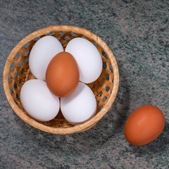 Poster - several fresh chicken eggs in a straw basket on a wooden background. Healthy eating concept.