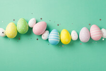 Top View Photo Of Easter Decorations Glowing Confetti And Row Of Multicolored Easter Eggs On Isolated Teal Background With Copyspace