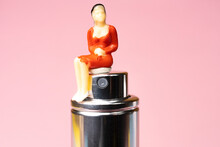A Statuette Of A Woman Sitting On A Perfume Bottle	